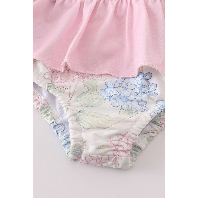 zoomed in view of the lower part of the swimsuit-has light green leaves and blue flowers that are found throughout the swimsuit