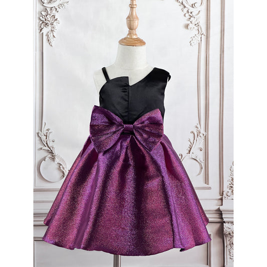 A metallic purple bow dress with a metallic purple bow, black at the top, thick sleeve on left, thin shoulder strap on the right, displayed on a wooden stand in with a elegant background