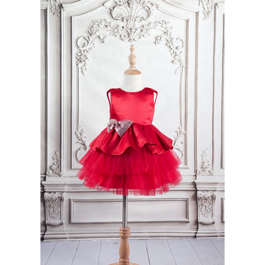 A red dress with red tulle with a light pink bow with gold sequin displayed on a mannequin against an elegant background, side view