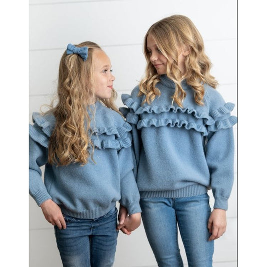 Two people wearing matching blue sweaters with ruffled shoulders against a white background