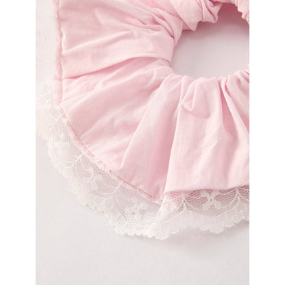 Pink scrunchie with lace trim on a light gray background