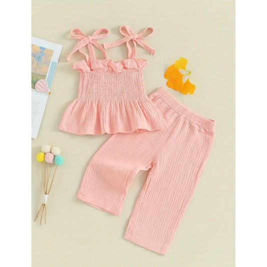 A pink sleeveless cami top with ribbons to tie bow for each shoulder and matching stretch pants for toddlers. light pink